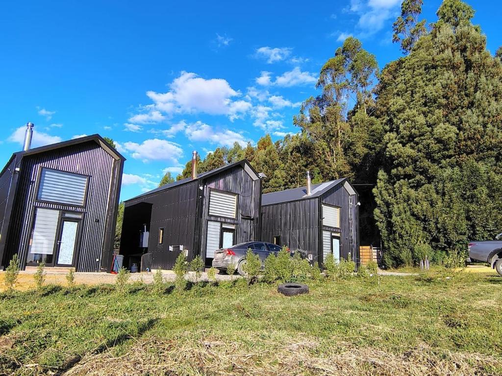 a black house with a car parked in a field at Cabaña Valdivia in Valdivia