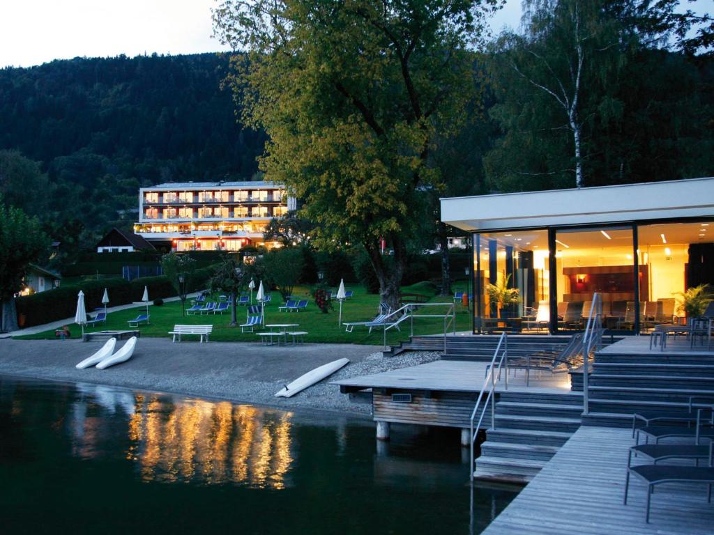 a building next to a body of water with a building at Seehotel Hoffmann in Steindorf am Ossiacher See