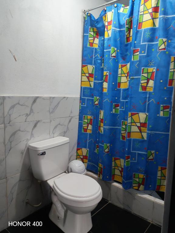 a bathroom with a toilet and a blue shower curtain at Casita de camucha segundo piso in Chincha Baja