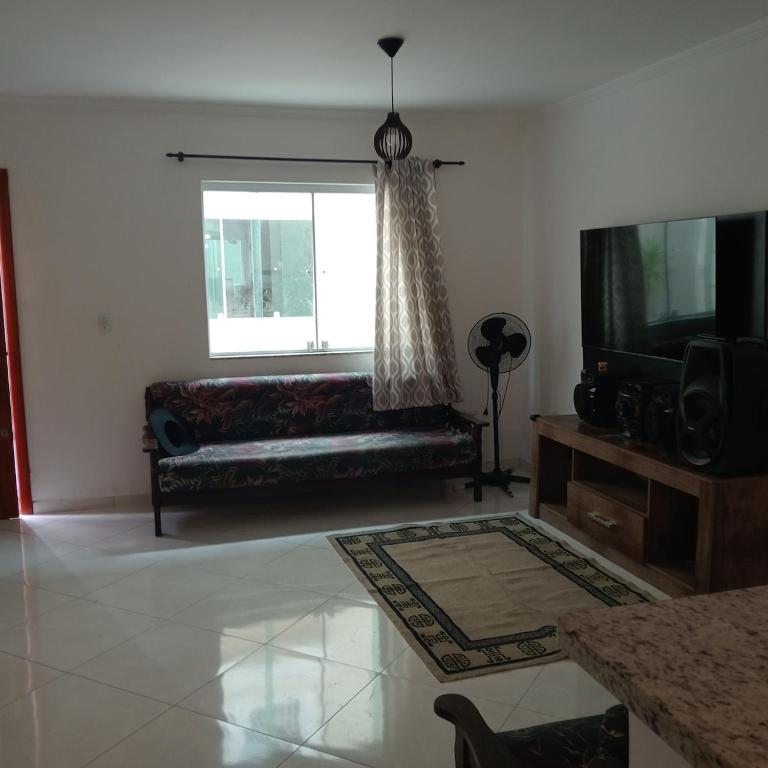 a living room with a couch and a television at Enseada Perto da praia Guarujá com vaga de garagem in Guarujá