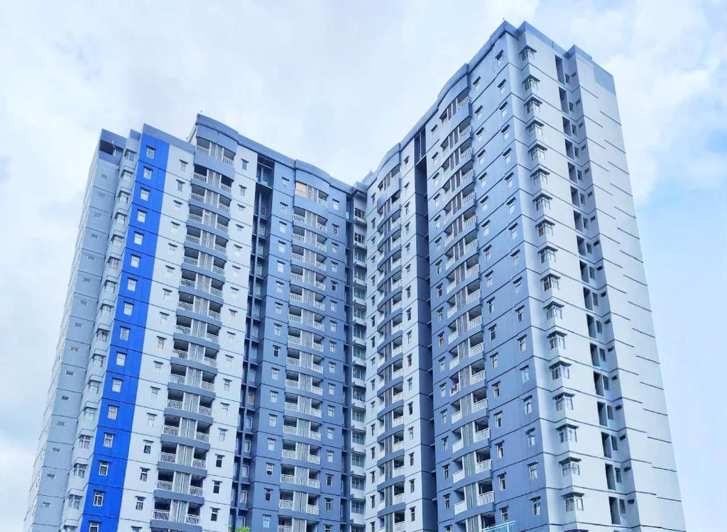 a tall apartment building with blue windows at Grand Serpong Hotel in Panunggangah