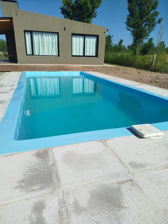 a blue swimming pool in front of a house at Casa a estrenar En Trapiche - Pileta privada in Trapiche