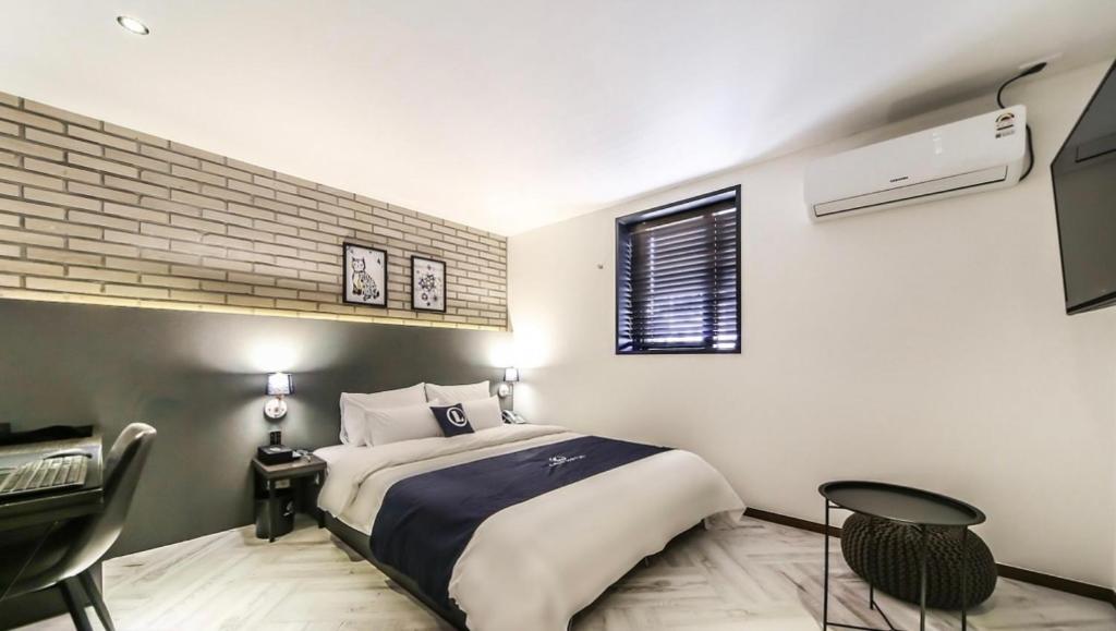 a bedroom with a bed and a desk and a window at 엘루이호텔 in Busan