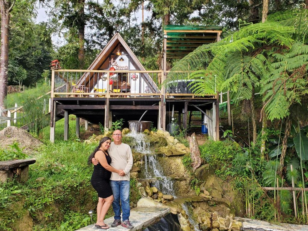 a man and woman standing in front of a tree house at Finca Agrópolis de Silvania in Silvania