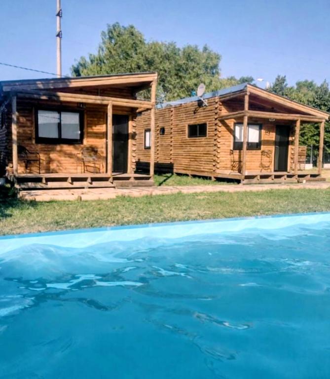 a log cabin with a swimming pool in front of it at Cabañas Olavarría in Olavarría