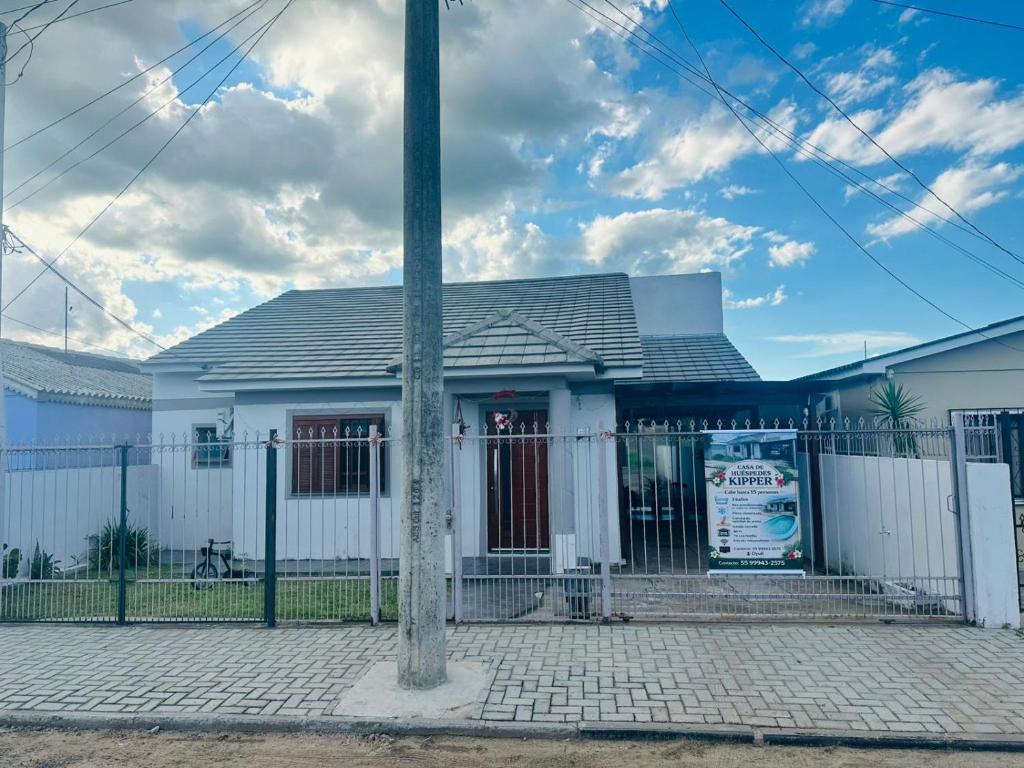 a white house with a fence and a pole at Casa de Hóspedes Kipper in São Gabriel