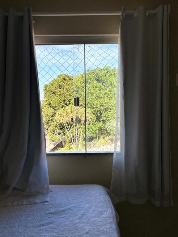 a bedroom with a window with a view of a mountain at Aconchego na praia in Ilhéus