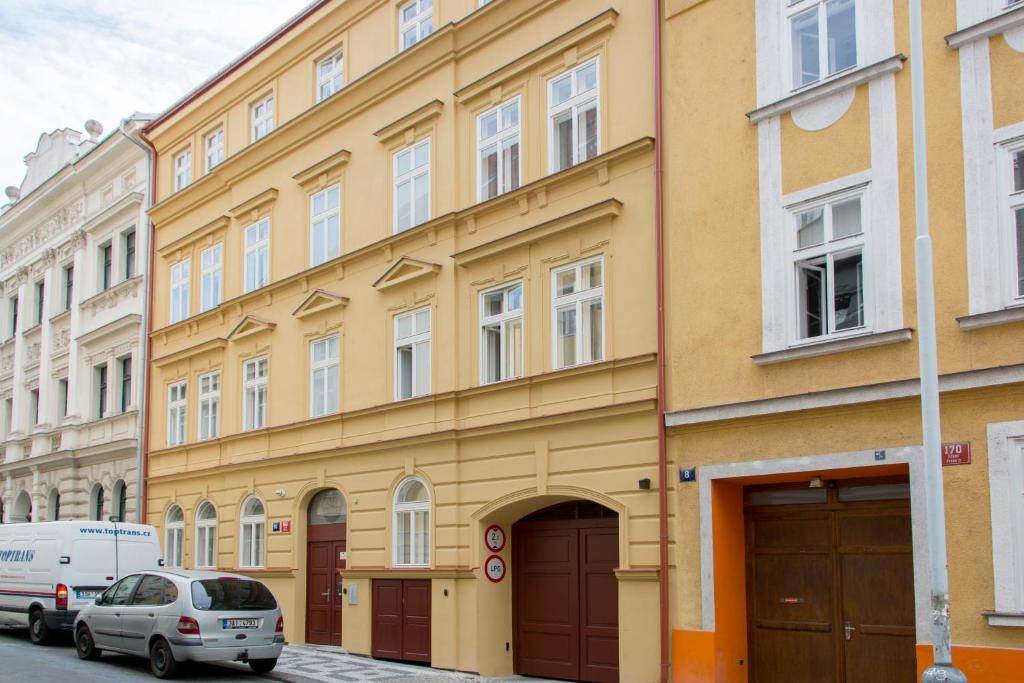 a yellow building with cars parked in front of it at Limes Apartments in Prague