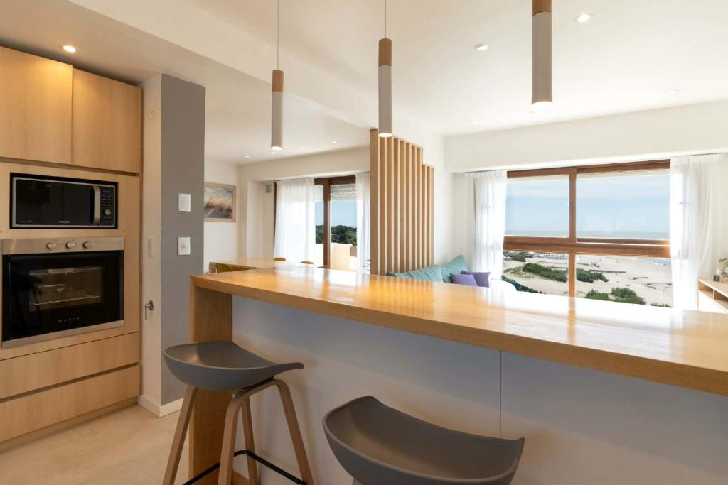 a kitchen with a counter and a bar with a chair at Villa Gesell departamento frente al mar in Villa Gesell