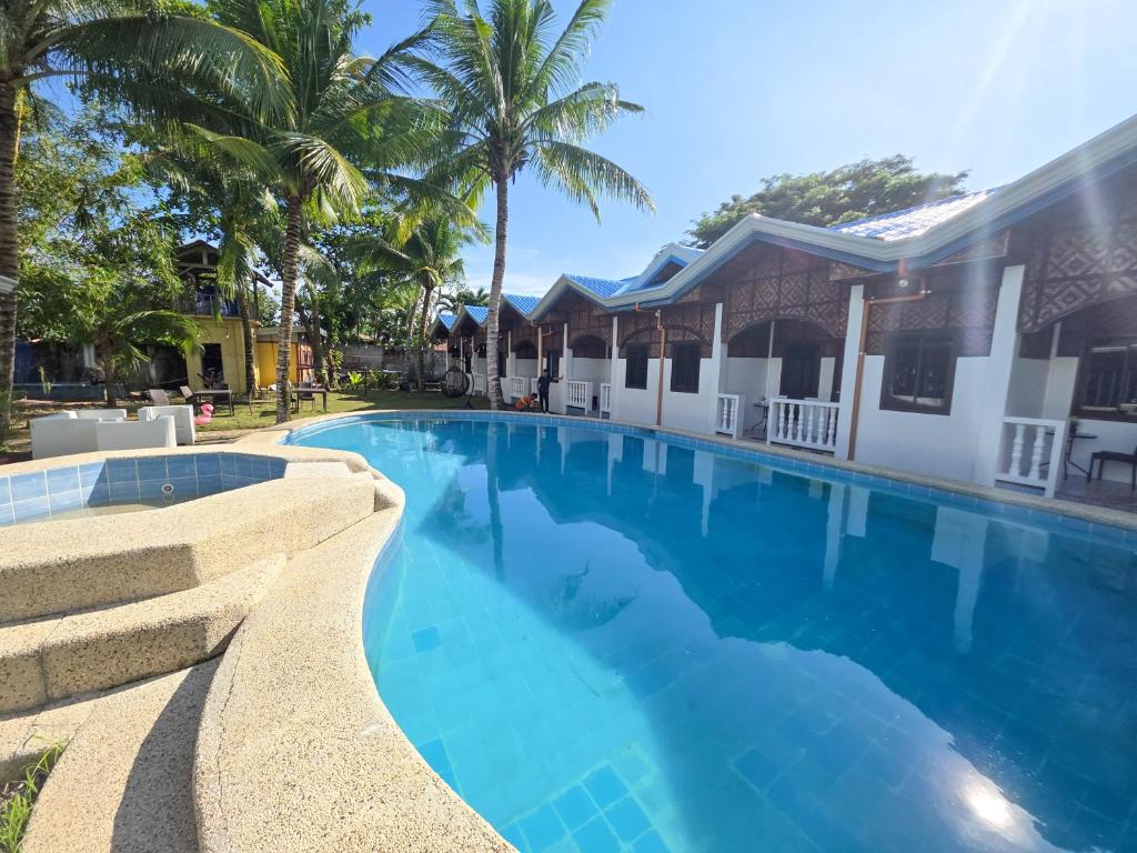 a large blue swimming pool next to a house at Golden palm rise resort in Libaong