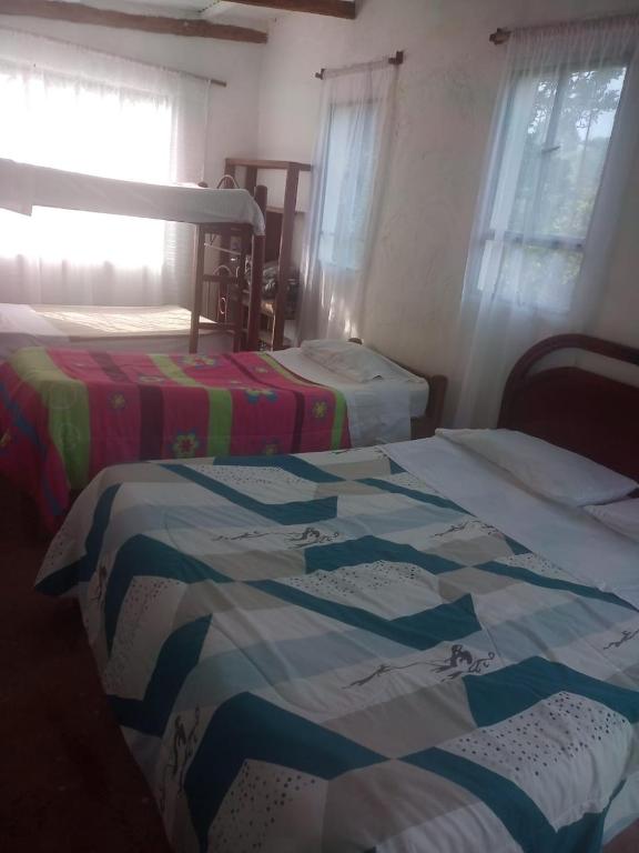 ein Schlafzimmer mit zwei Betten und einem Fenster und einem Bett sidx sidx sidx in der Unterkunft Harmony Risk in Sasaima