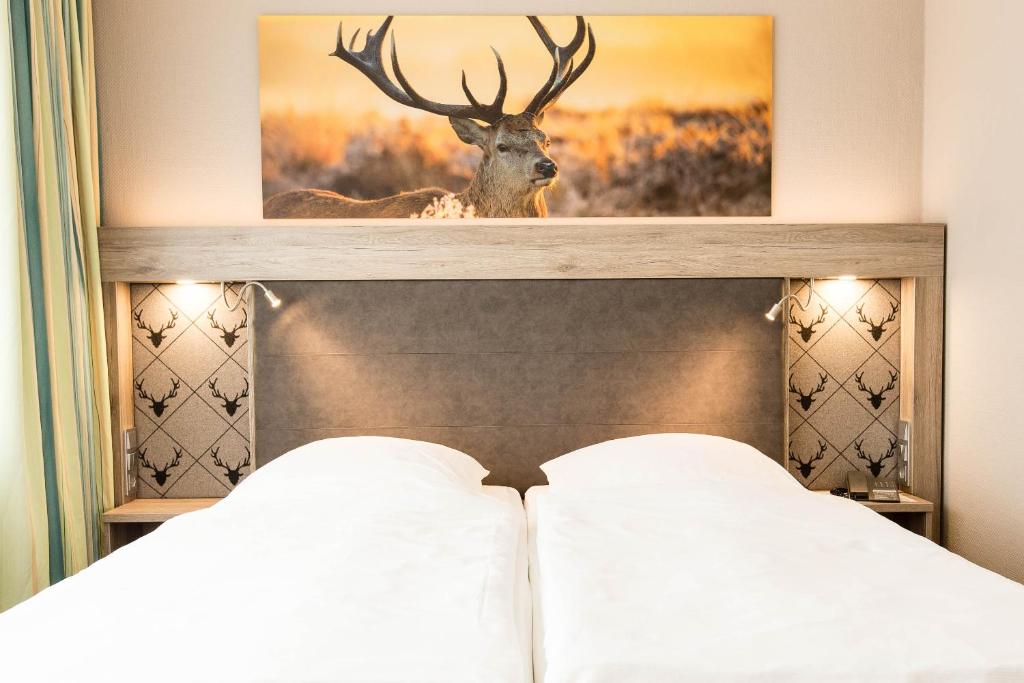 ein Bild eines Rehs über einem Bett in einem Hotelzimmer in der Unterkunft Hotel Bavaria Oldenburg in Oldenburg