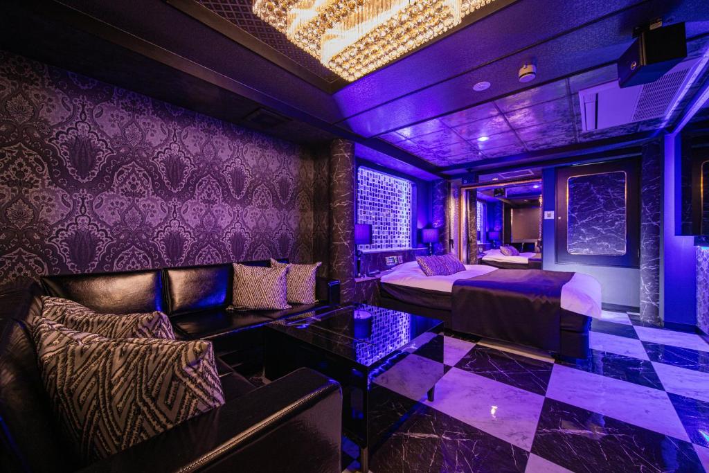a room with purple lighting and a bed and a couch at HOTEL FIVE -Adult Only- in Osaka