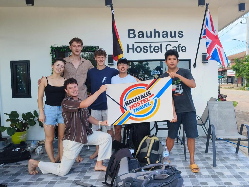 een groep mensen die poseren voor een foto met een bord bij Bauhaus Hostel Cafe in Don Sak