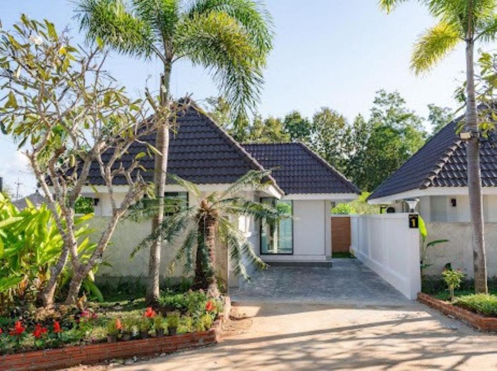 a house with palm trees and a driveway at Villanin Hotel & Spa Golden Triangle in Ban Wiang Nuea
