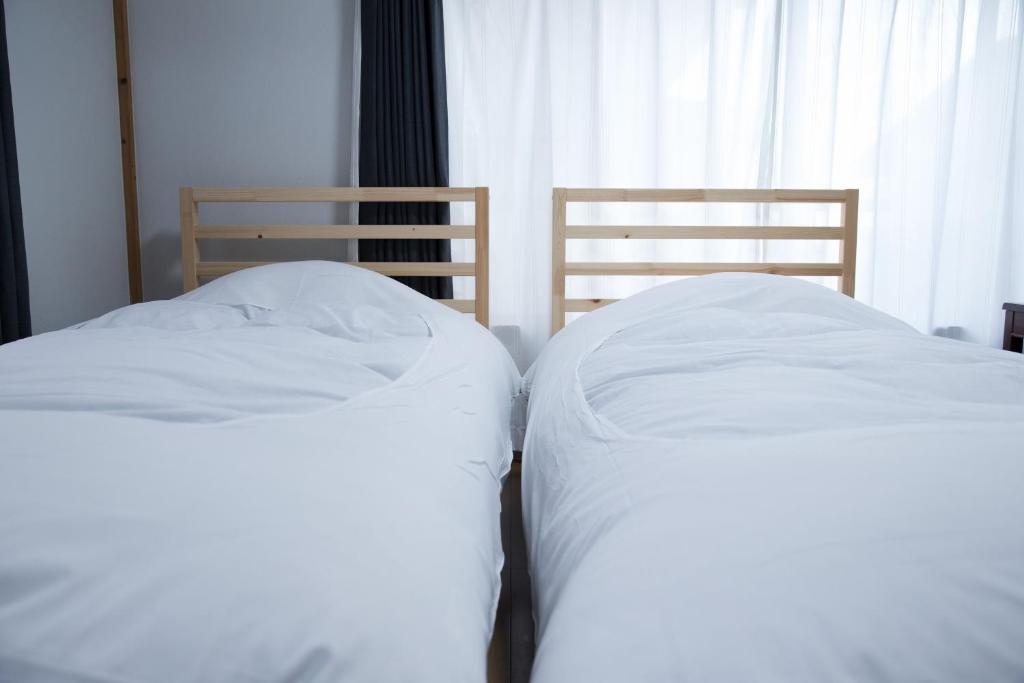 two beds with white sheets sitting next to a window at 伊豆の宿 静川 in Ito