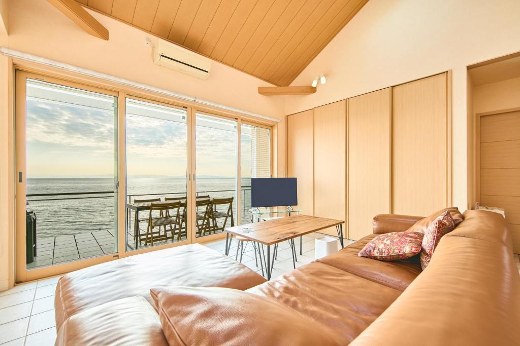 a living room with a couch and a view of the ocean at Villa Acatella in Awaji