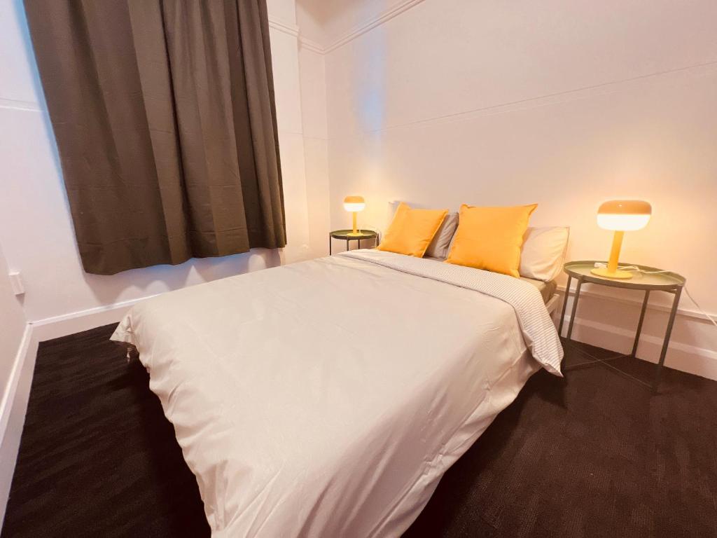 a bedroom with a large white bed with two lamps at Utopia31 Hostel - formerly Frienz Backpacker in Auckland