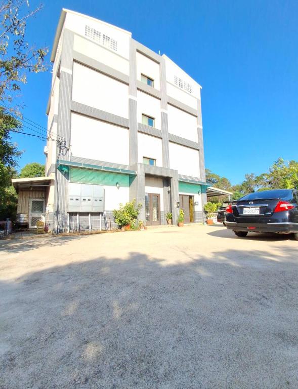a white building with a car parked in front of it at Kinmen Dongshan B&B in Jinning