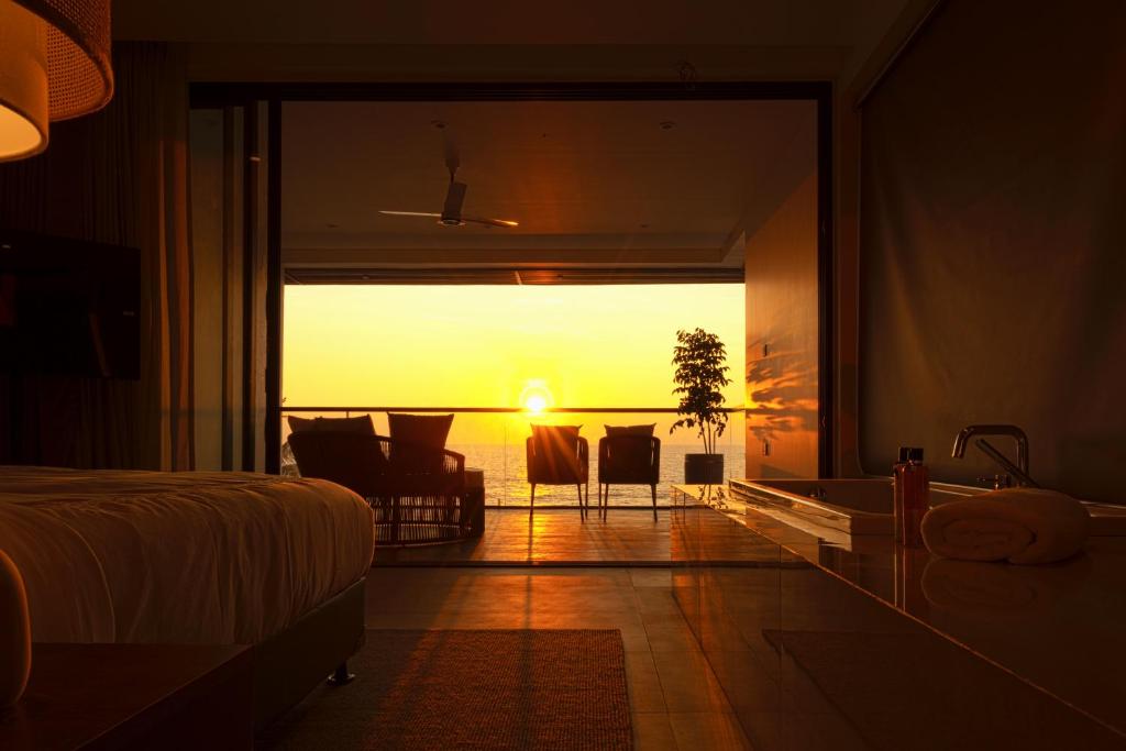 a bedroom with a bed and a view of the sunset at Sukavi in Paravūr