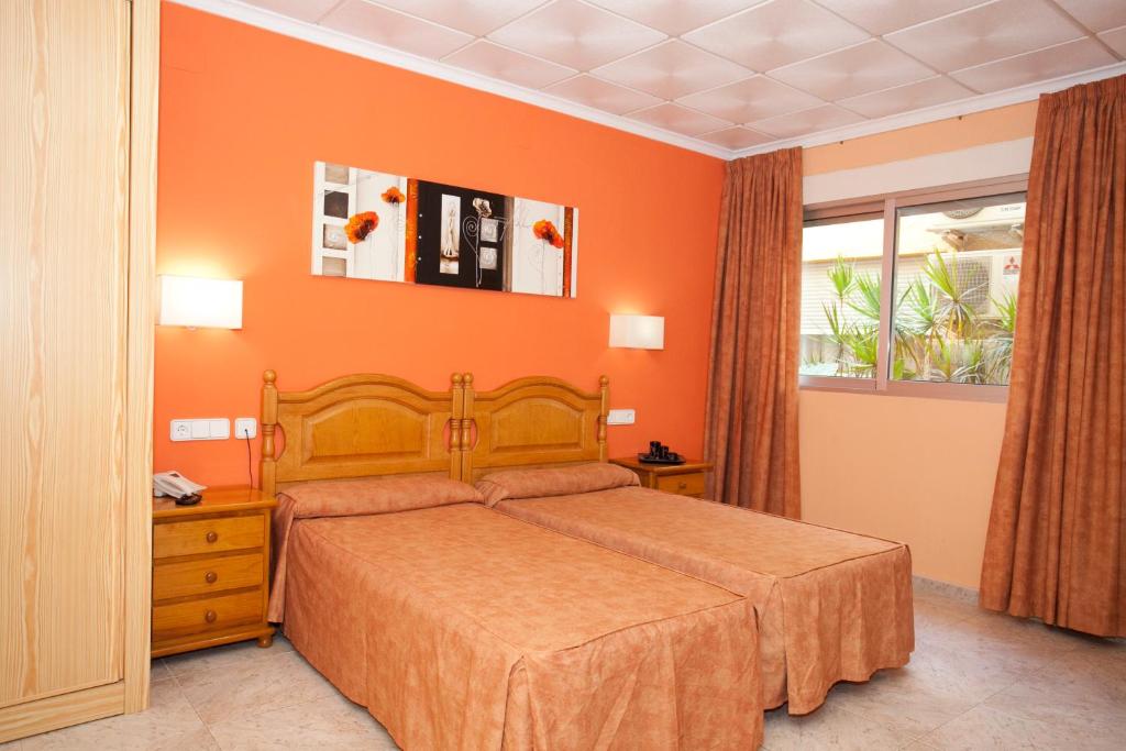 a bedroom with a bed with an orange wall at Hotel Noguera El Albir in Albir