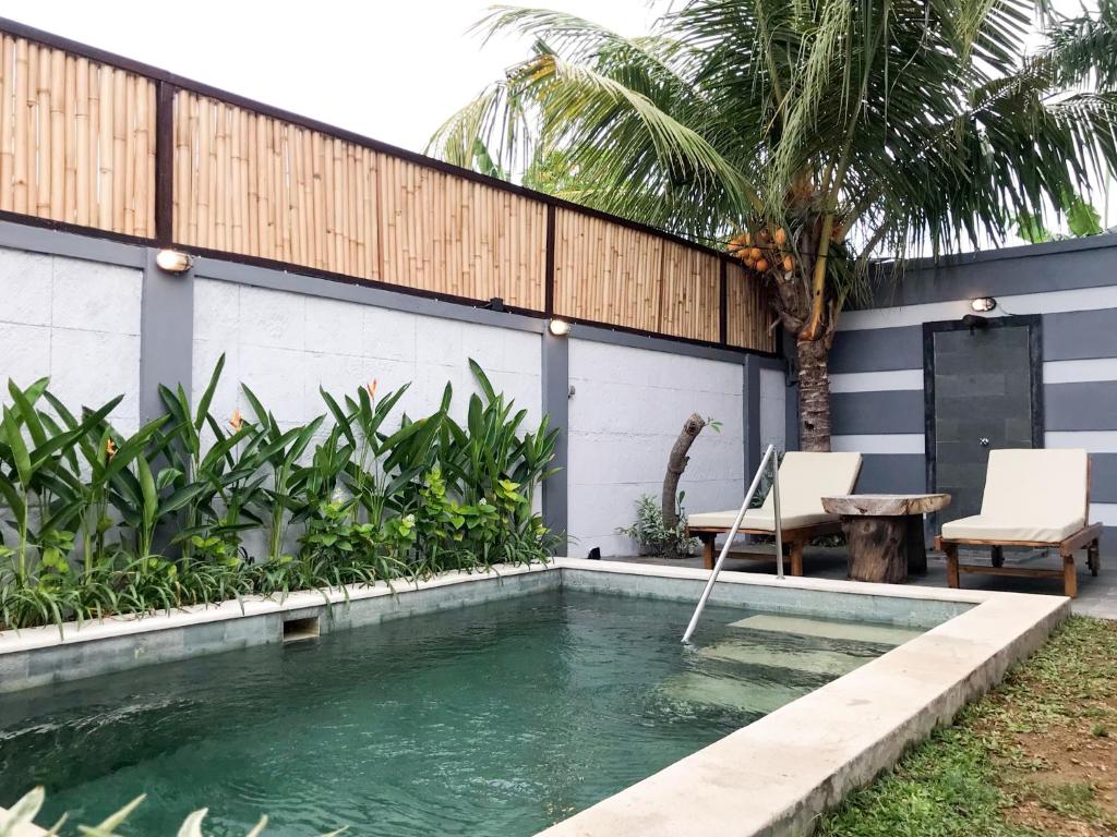 a swimming pool in front of a house with a palm tree at Telaga Villa Siki in Mantaak
