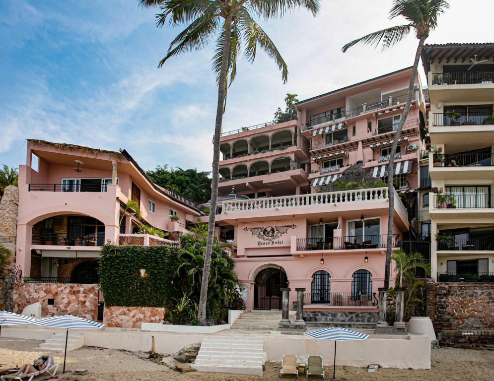 a pink building with palm trees in front of it at Quinta Maria Cortez Beach Hotel in Puerto Vallarta