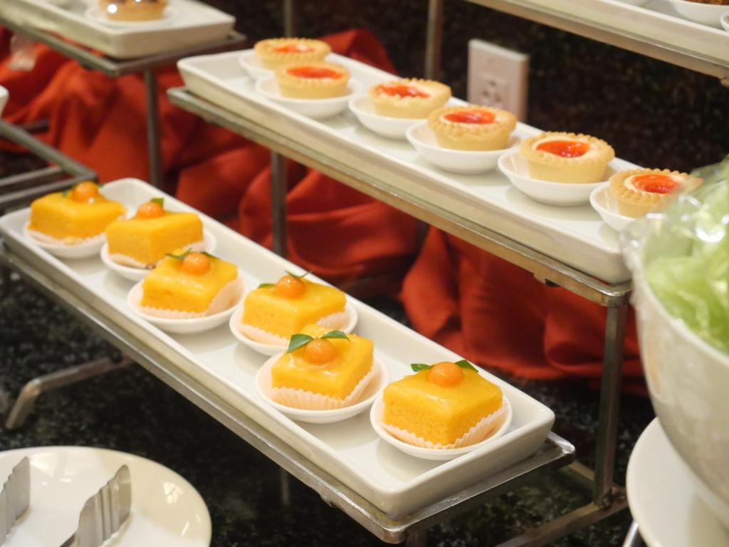 Individual fruit-topped desserts arranged on tiered buffet trays.