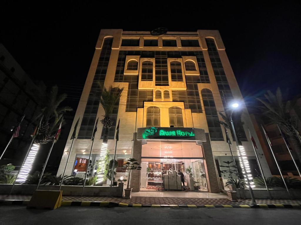 فندق سبار في عمّان: مبنى شاهق ذو واجهة متجر ليلاً