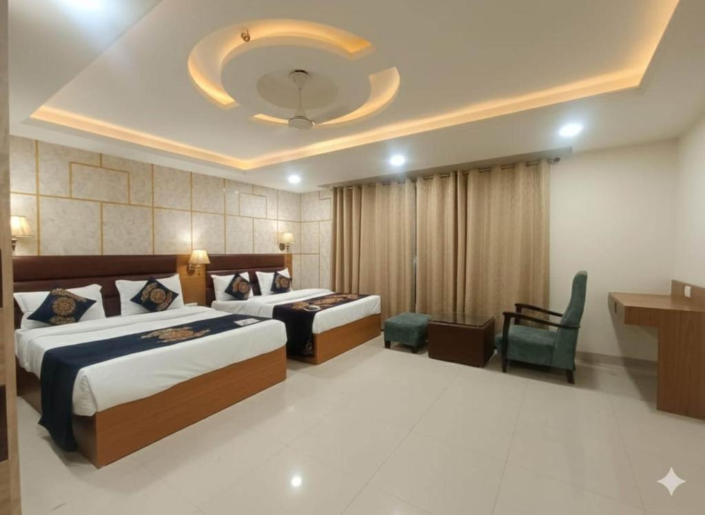 una stanza d'albergo con due letti e una sedia di Hotel Grand Suites By D capitol Near Delhi Airport a Nuova Delhi
