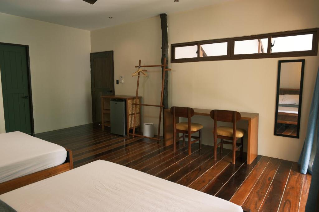 a room with two beds and a table and two chairs at Easy Does It Guesthouse Siargao in General Luna