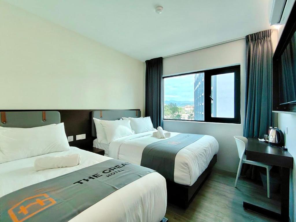 a hotel room with two beds and a desk and a window at The Great Hotel Greenhill in Ipoh