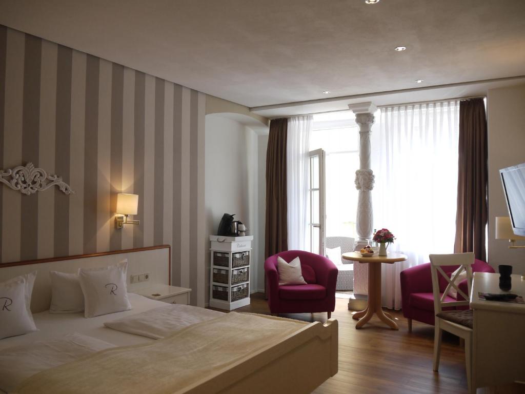 リンダウにあるホテル ラッツストゥーベンのベッドと椅子付きのホテルルーム