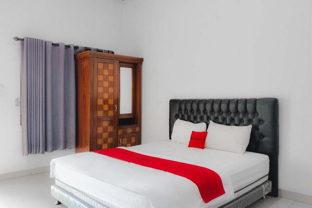 a bedroom with a bed with a red blanket at RedDoorz at Trans Hotel Cilegon in Toyamarta