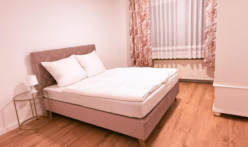 a small bedroom with a bed with white sheets and a window at HANOSAN Apartments Familienhaus 4 Zimmer 125 m2 in Garbsen