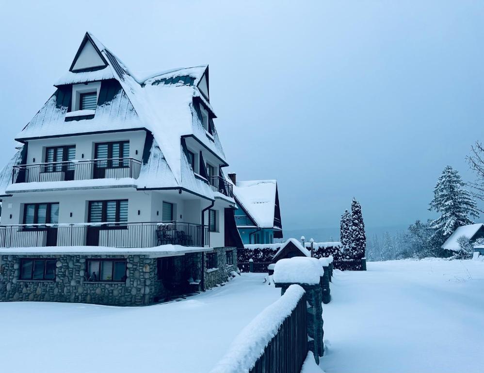 een huis bedekt met sneeuw naast een hek bij Apartamenty 1000m npm Murzasichle in Murzasichle