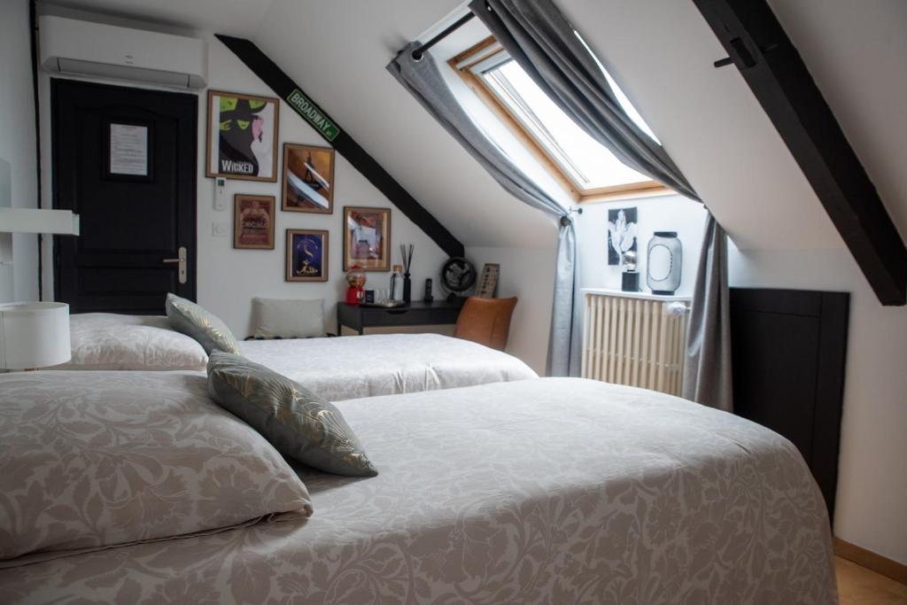 two beds in a room with a window at Les chambres du Bocage - Chambre Marylin in Bressuire