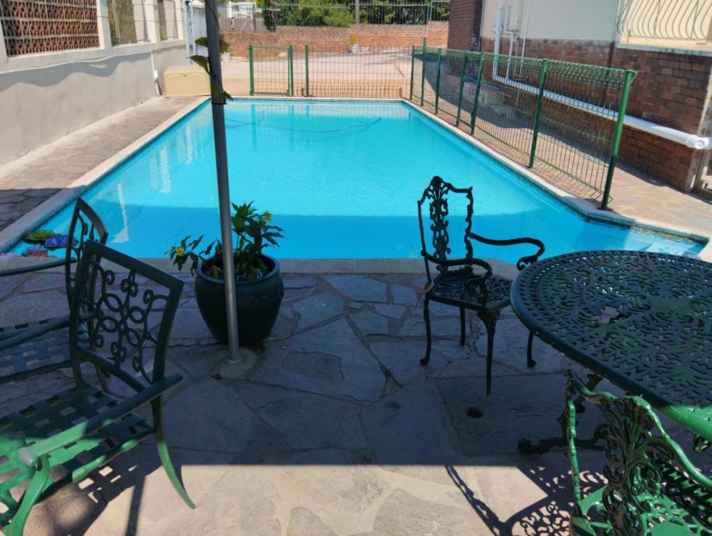 a swimming pool with two chairs and a table and a table and chairs at Nkosazana Guest House in Durban
