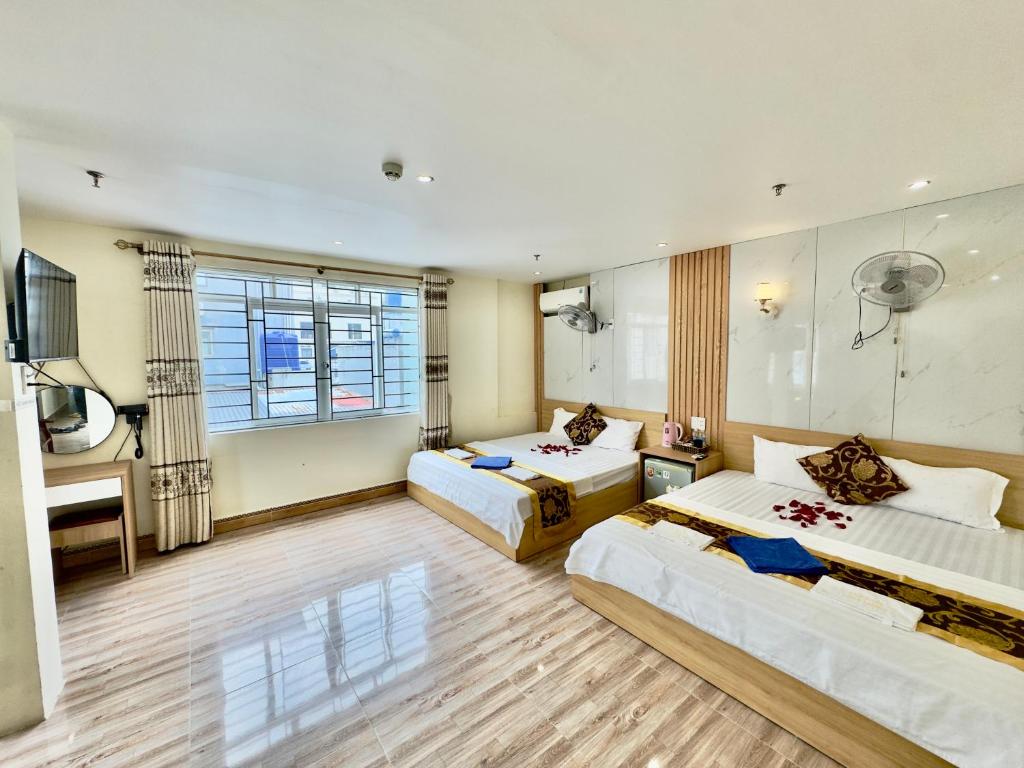 a hotel room with two beds and a television at Văn Phượng Hostel in Cat Ba