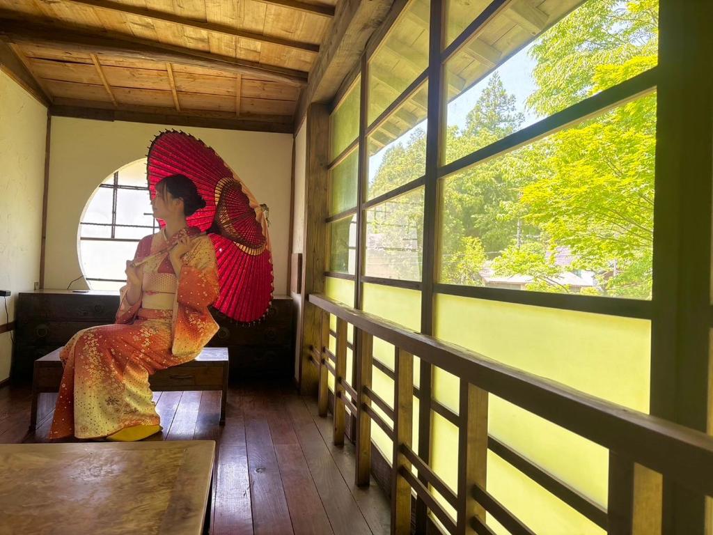 a woman sitting on a bench holding an umbrella at Guest House時音 in Joetsu