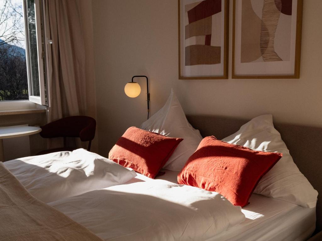 a bed with red and white pillows on it at Berghotel Lindenhof in Siegsdorf