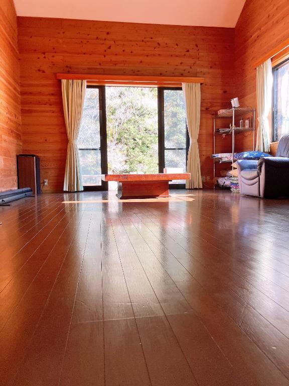 a living room with a hard wood floor and windows at 川辺の宿-Kawabe-BBQ-川遊び in Hanno