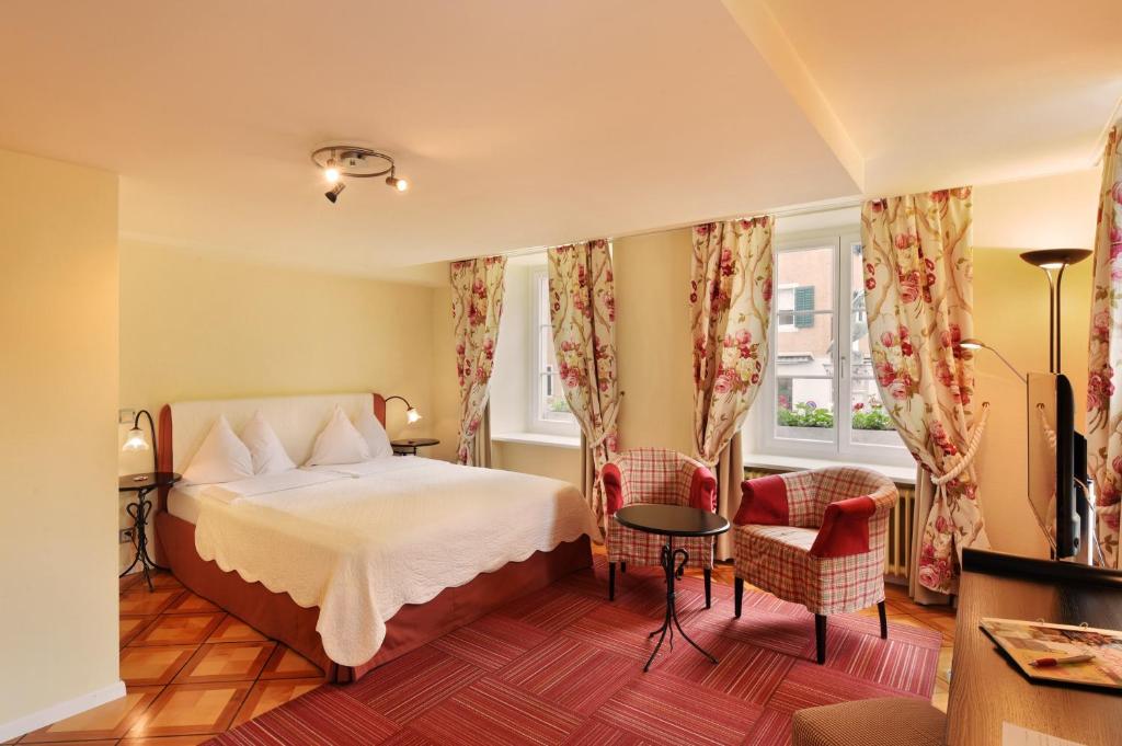 a hotel room with a bed and two chairs at Romantik Hotel Schwan in Horgen