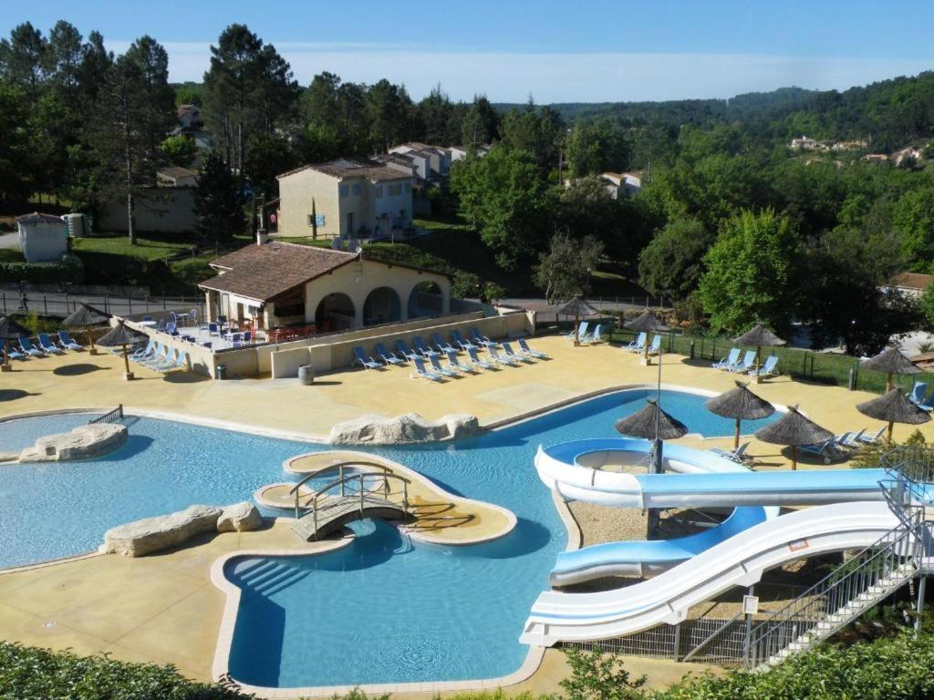 a large pool with slides and umbrellas at a resort at Appartement dans résidences de vacances in Salavas
