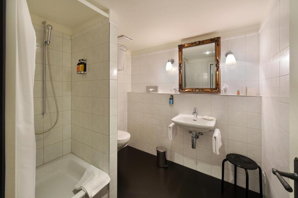 a bathroom with a sink and a tub and a toilet at Romantik Hotel Schwan in Horgen