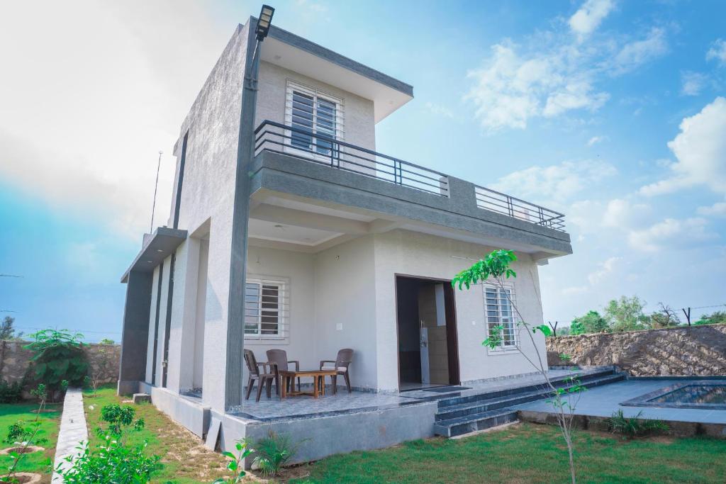 a small white house with two chairs and a porch at Silverleaf Homestay in Borāj