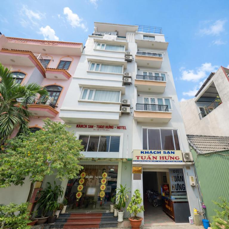 a tall white building with a restaurant in front of it at Tuấn Hưng Hotel HCM in Ho Chi Minh City
