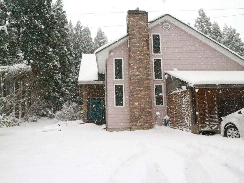 a house covered in snow with a car in the driveway at Pension Ciffon in Kitakami