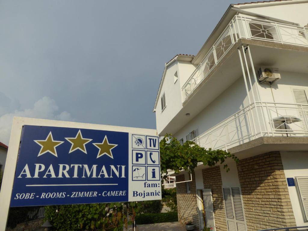un edificio con un cartello per un appartamento con delle stelle sopra di Apartments Bojanic a Vodice