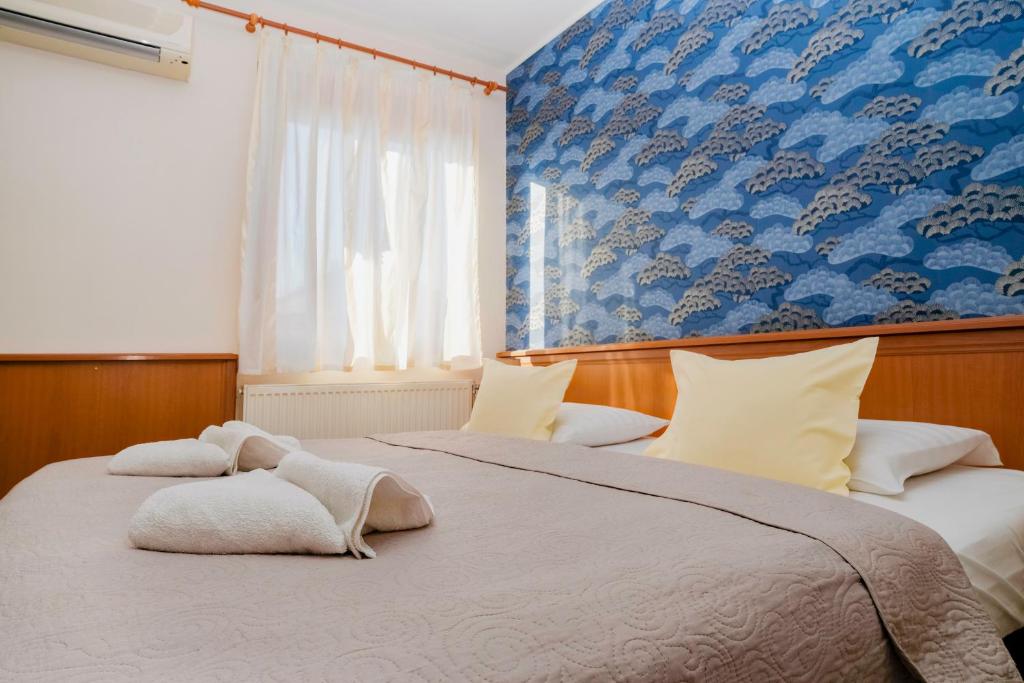 two beds in a bedroom with a blue wall at König Hotel in Pécs